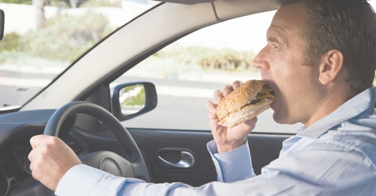 man eating burger in car